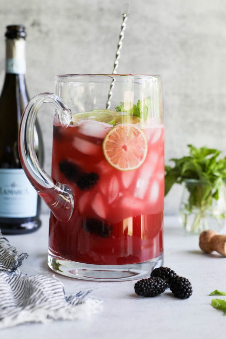 A large pitcher of blackberry lime prosecco topped with fresh lime juice, blackberries, and mint. 
