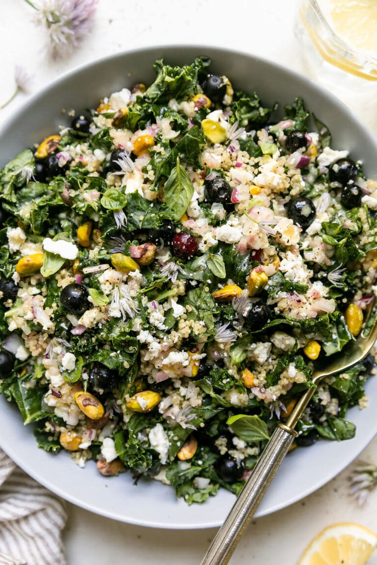 Overhead view of quinoa kale salad with blueberries and feta topped with flavorful lemony vinaigrette. 