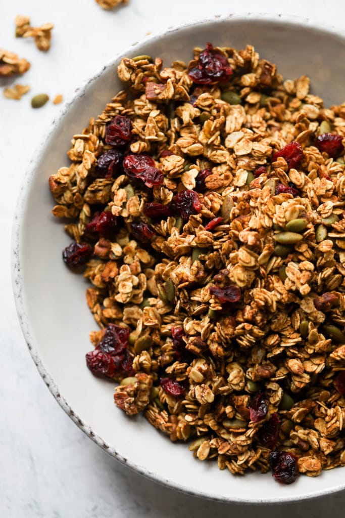 A bowl of crisp granola with pumpkin seeds and dried cranberries. 